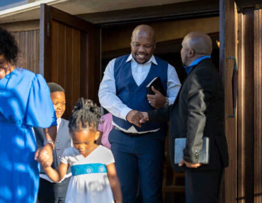 Family leaving the church after attending service, Father thanks the Pastor with a handshake